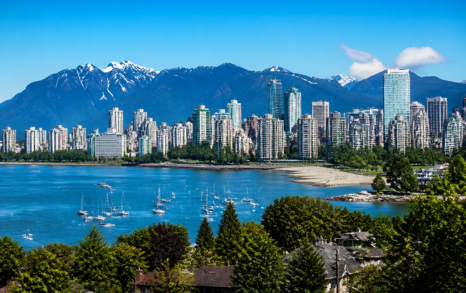 Vancouver's downtown skyline across English Bay with the North Shore mountains behind on a clear summer day